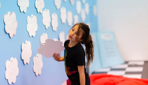 A child looking contemplatively at a wall full of self care ideas written on cloads 