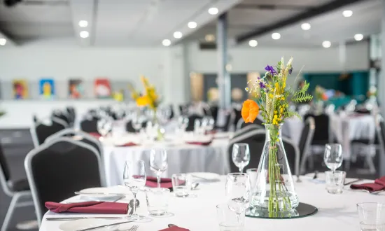 Tables dressed for a dinner party with flowers on top. 
