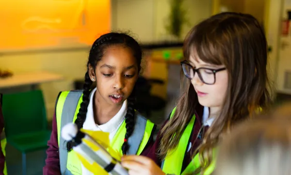 Two children in high-vis vests looking concentrated whilst putting together a rocket 