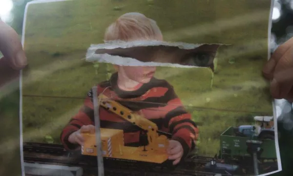 Ripped photograph of young child with eyes showing through