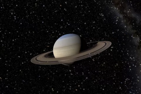 Saturn and its rings in front of a dark night sky with stars.