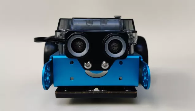 a front-on view of a blue mBot robot which looks like it has a smiley face