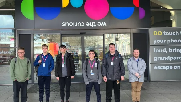 A group of six young people stood outside the front doors of We The Curious