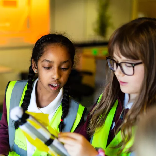 Two children in high-vis vests looking concentrated whilst putting together a rocket 
